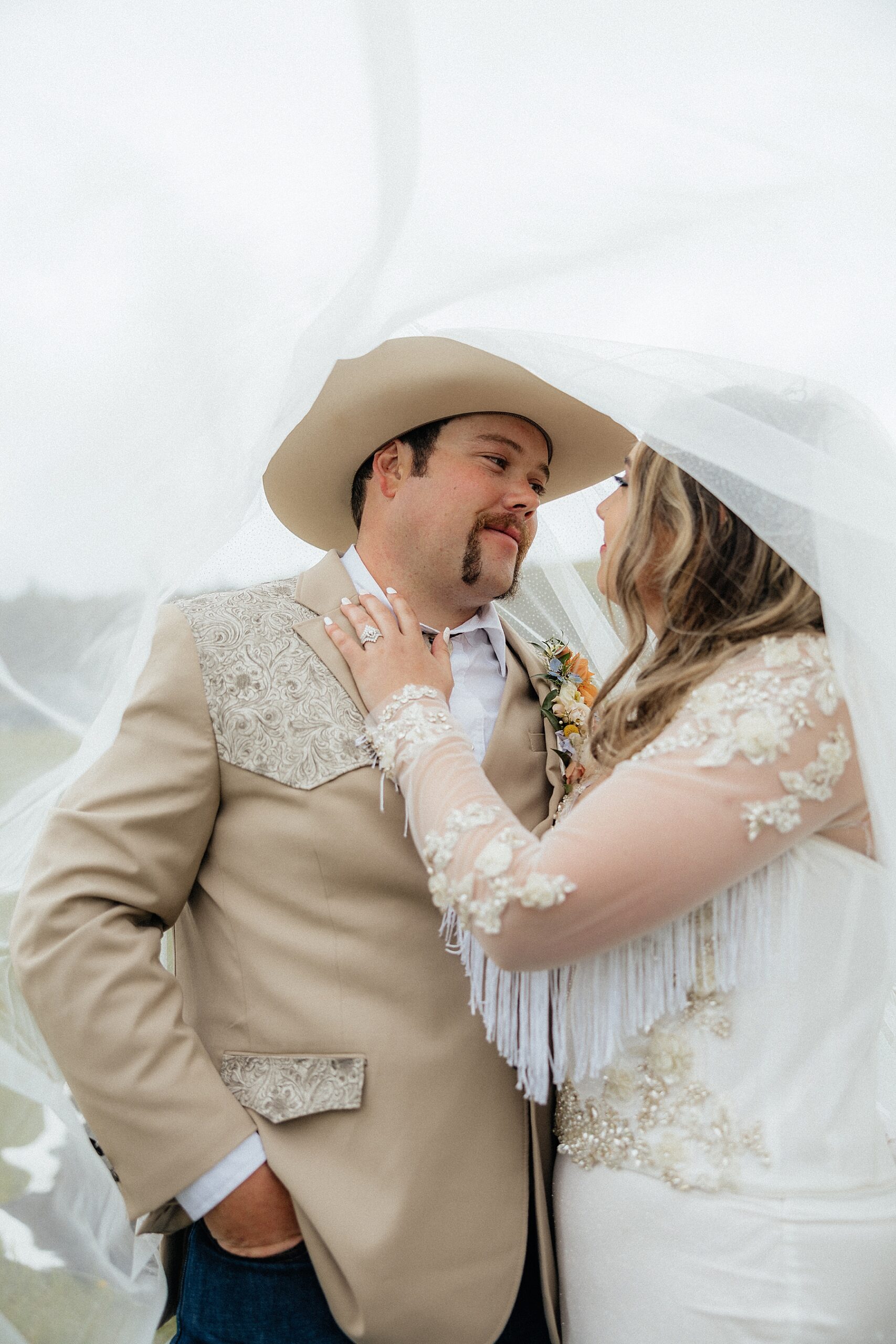 The bride and groom looking at each other under the veil.