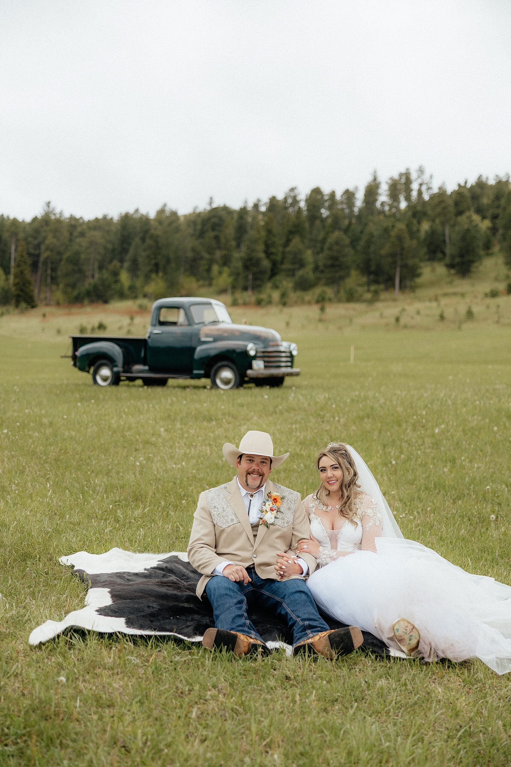 The bride and groom sitting on a cowhide rug.