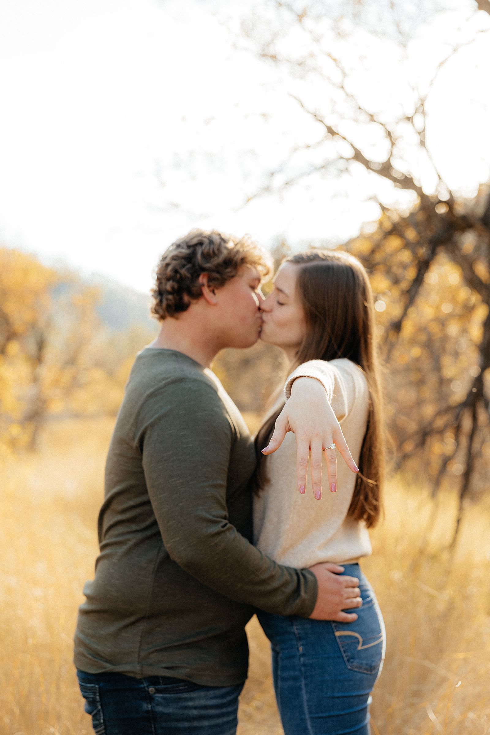 Hannah showing off her ring with beautiful fall colors behind her.