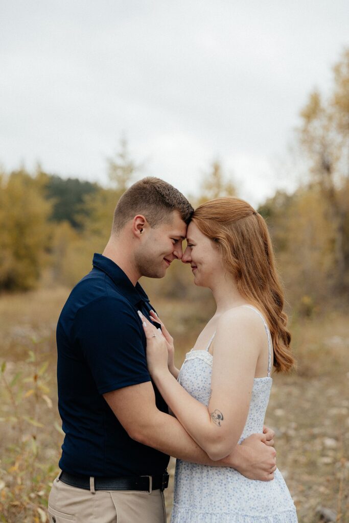 A couple standing forehead to forehead at their fall session in Spearfish Canyon.