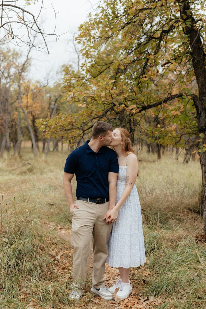 A couple kissing on an overcast day.