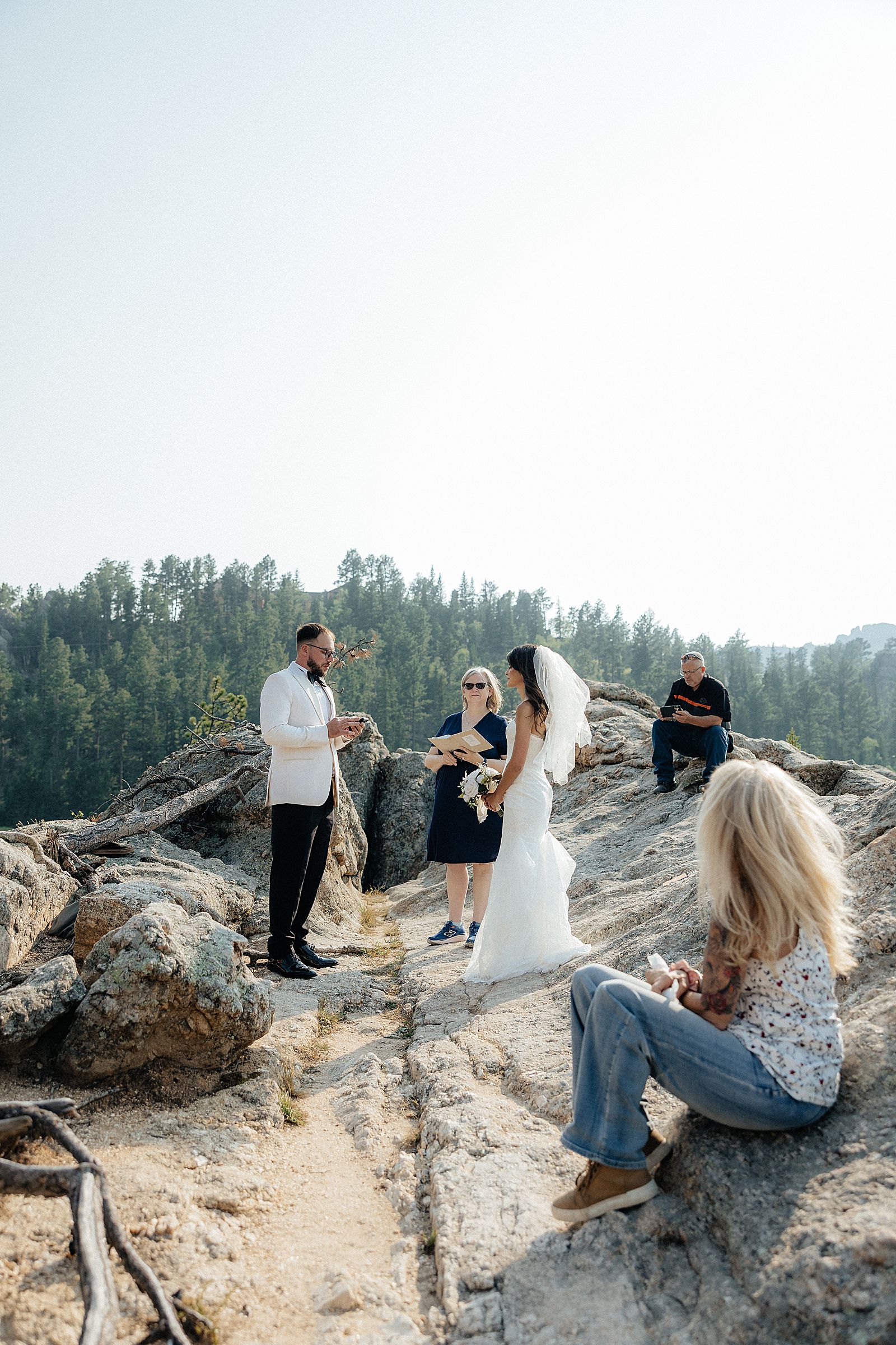 Phoebe and CJ exchanging vows on a granite rock formation overlooking Sylvan Lake