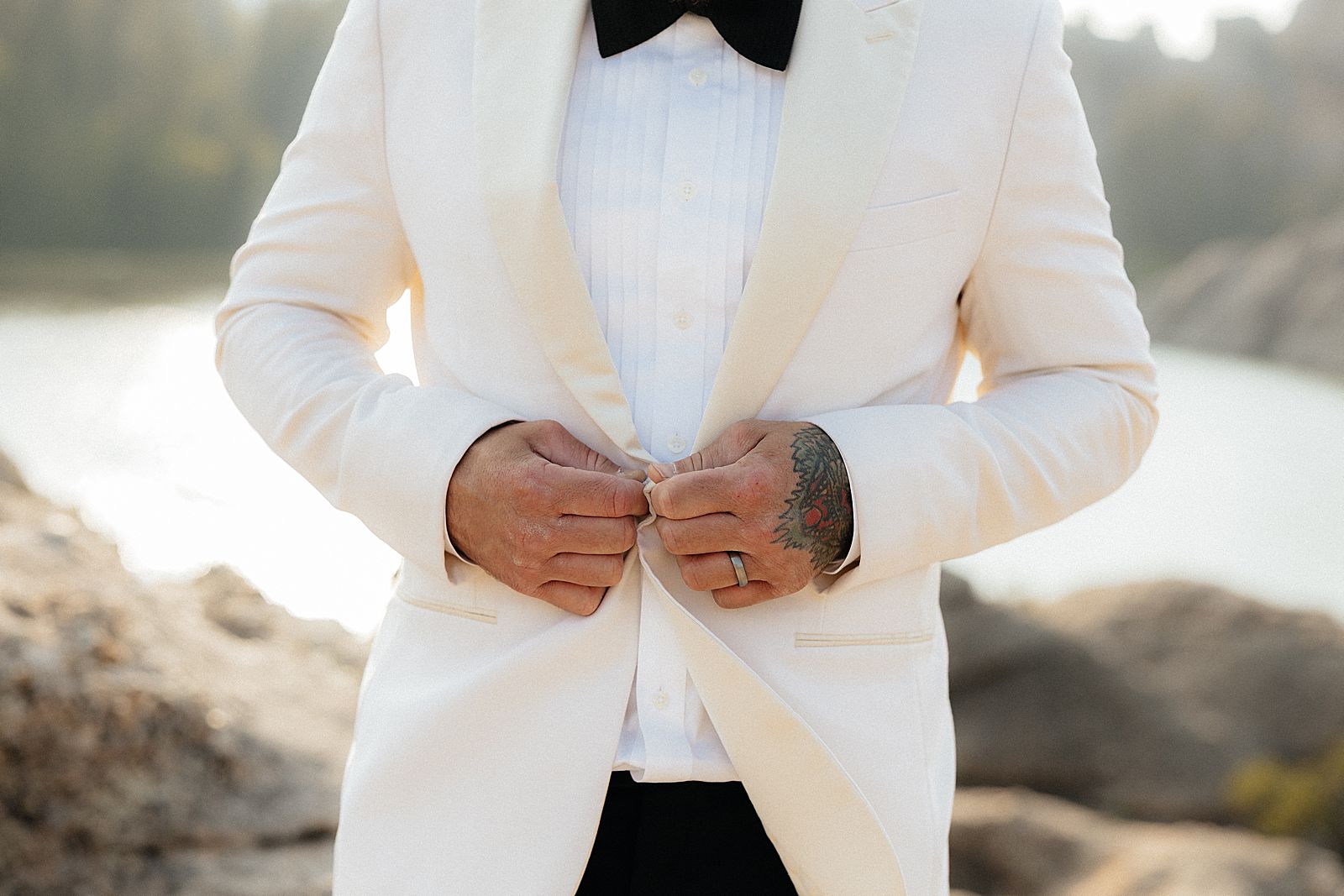 Close up of CJ buttoning his cream suit jacket
