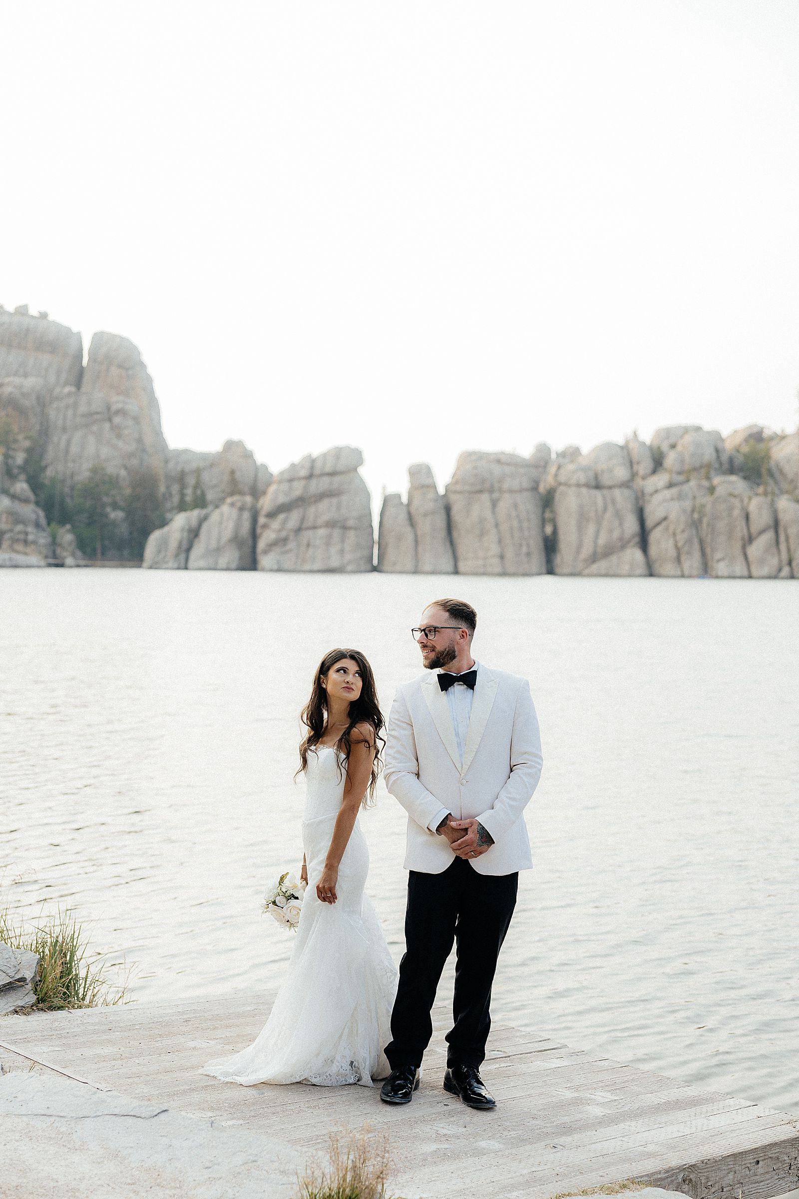 Wide view of newlyweds standing along the shoreline of Sylvan Lake